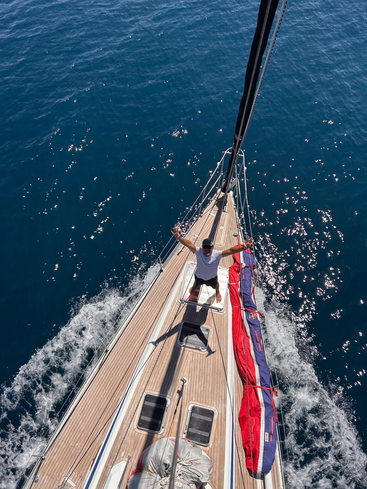 Looking down from the masthead as a crew member waves from the foredeck